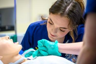 a picture of a nursing student practicing on a manikin